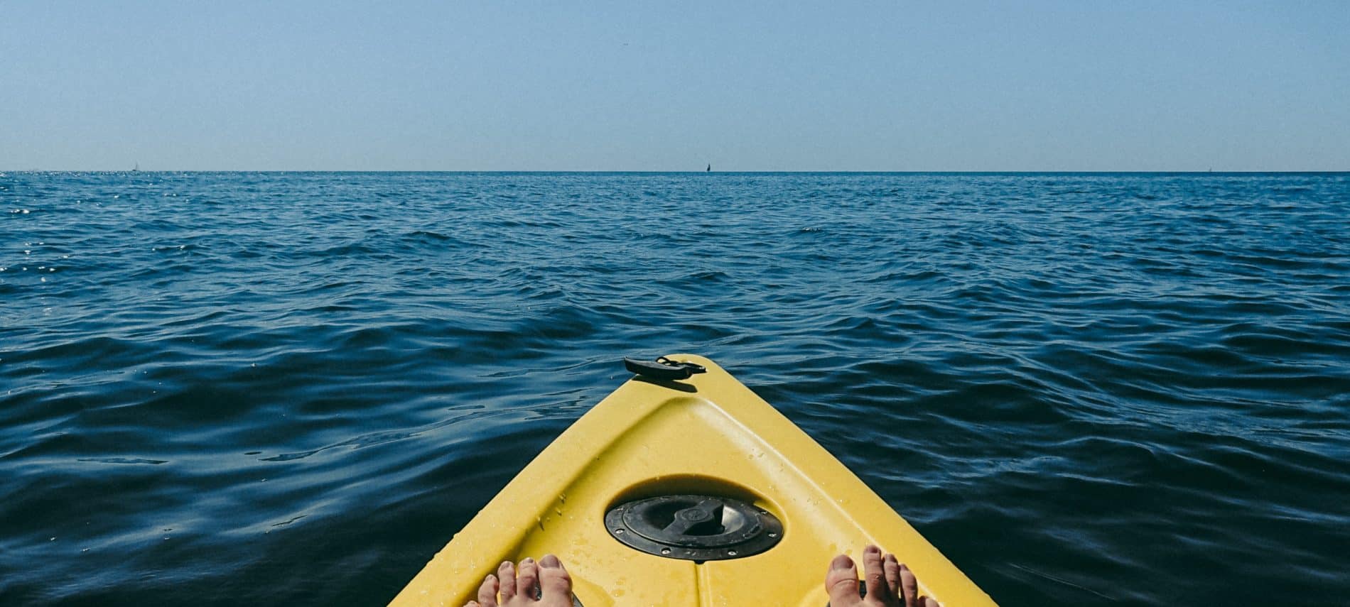 The nose of a yellow kayak on the open bay